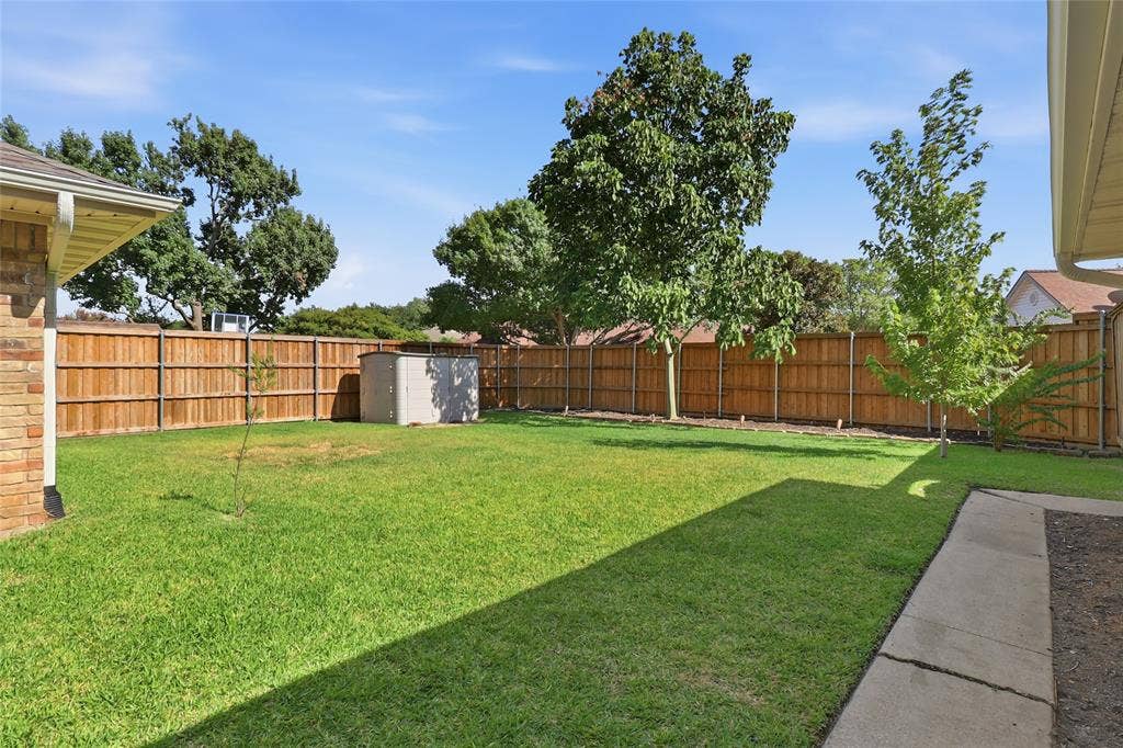 2808 Fountain Head Drive, Plano, TX 75023 Expansive grassy yard with mature trees, a privacy fence, and a storage shed
