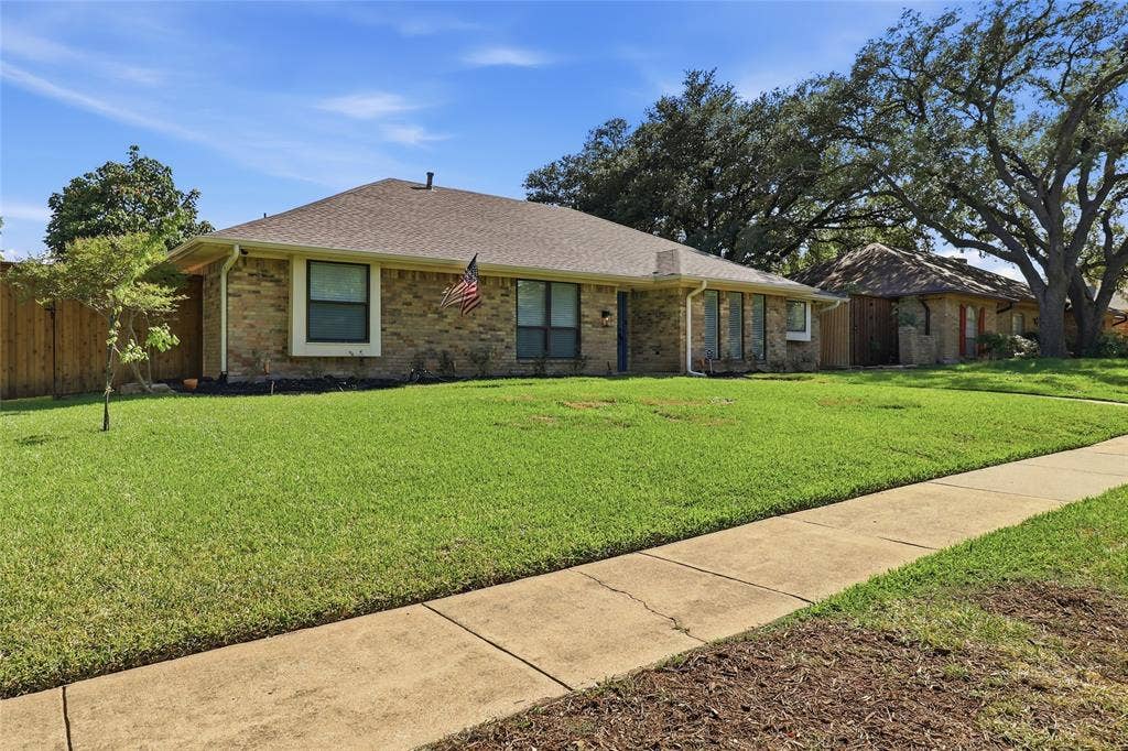 2808 Fountain Head Drive, Plano, TX 75023 Brick exterior, pitched roof, front yard with mature trees, established landscaping, and concrete sidewalk