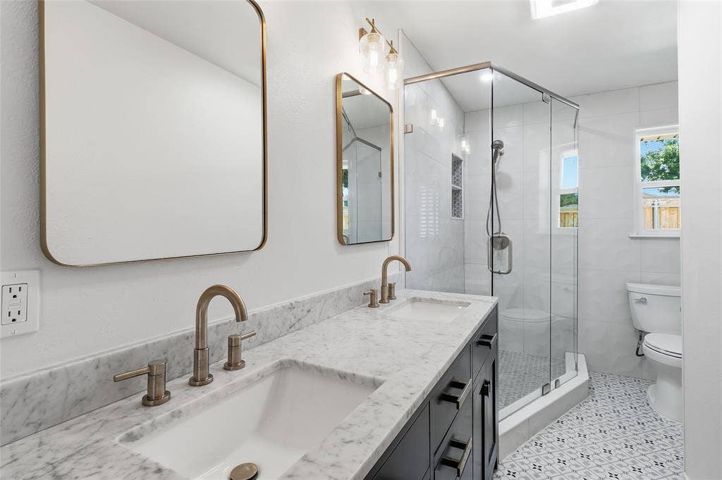 2808 Fountain Head Drive, Plano, TX 75023 Dual vanity with undermount sinks, marble-patterned countertop, and brass-finish fixtures