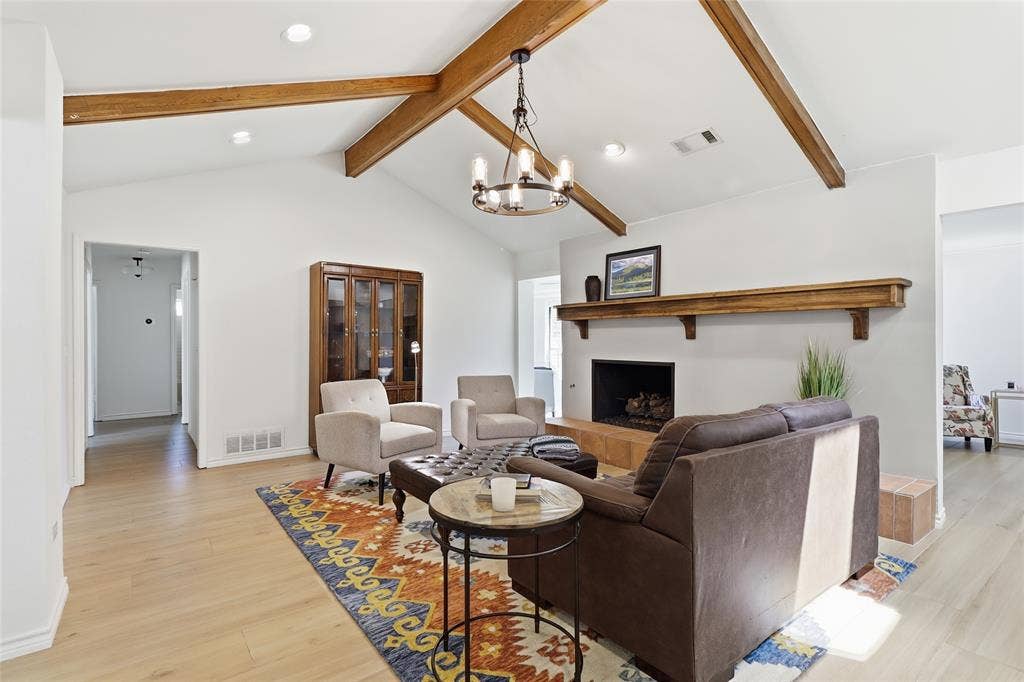 2808 Fountain Head Drive, Plano, TX 75023 Vaulted ceiling with exposed wood beams, wood-finish flooring, fireplace with a wood mantle, and an iron chandelier