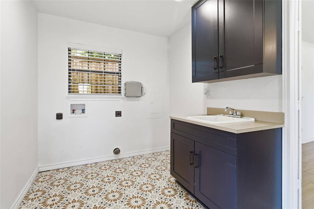 2808 Fountain Head Drive, Plano, TX 75023 Laundry area with patterned tile flooring, a window with blinds, dark cabinetry, and a utility sink with a quartz countertop
