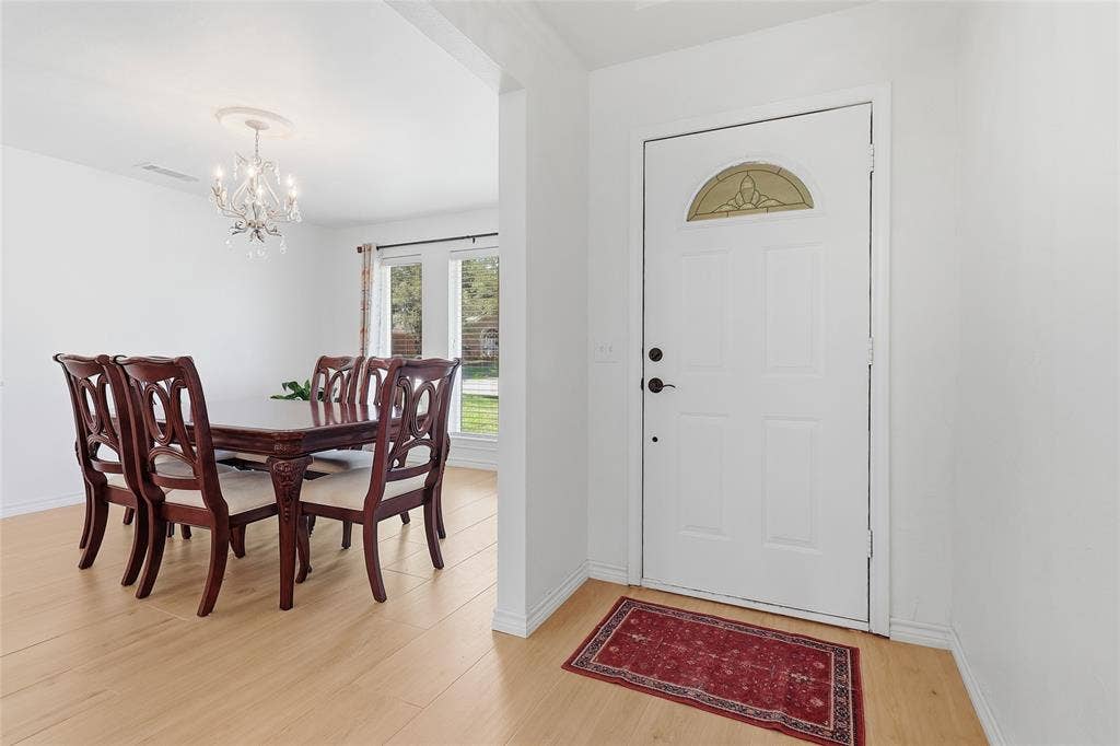 2808 Fountain Head Drive, Plano, TX 75023 Hardwood-finish flooring, white entry door with decorative glass, and a dining area featuring a chandelier