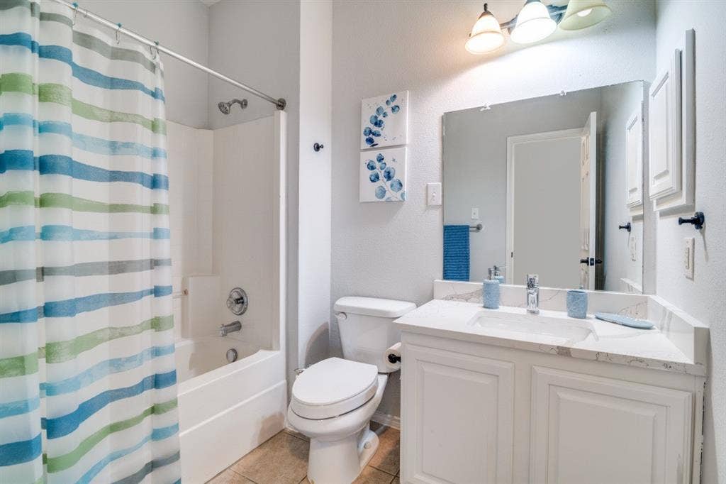 White vanity with a single basin sink and light-toned countertop