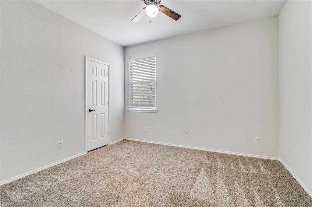 Neutral wall tones, textured carpeting, window with blinds, and a ceiling fan