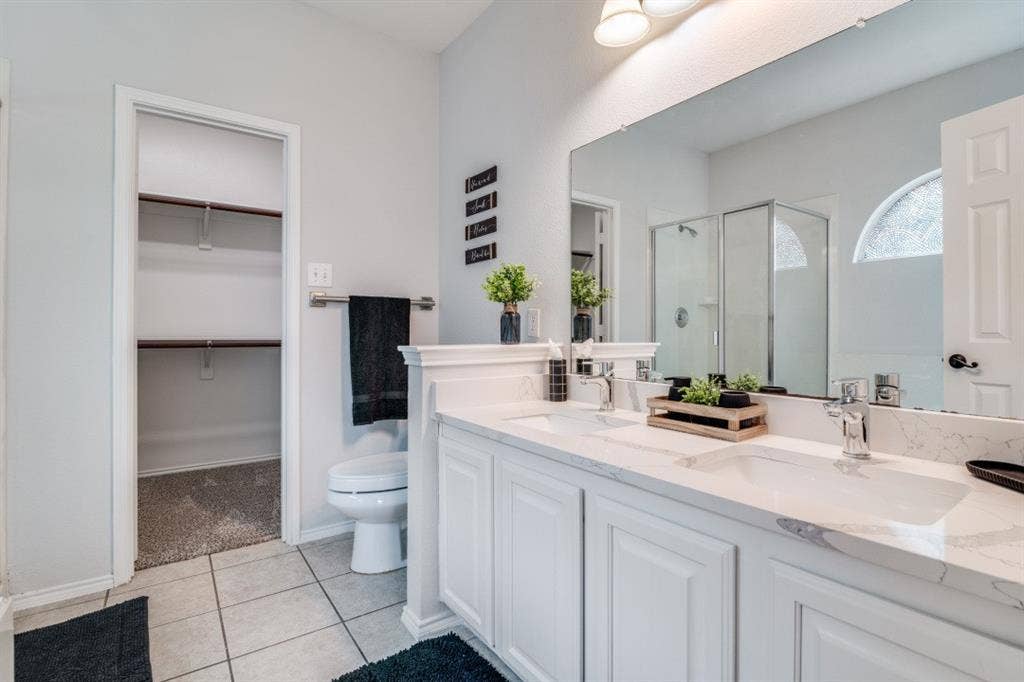 Dual vanity with white cabinetry, stone-look countertops, and chrome fixtures