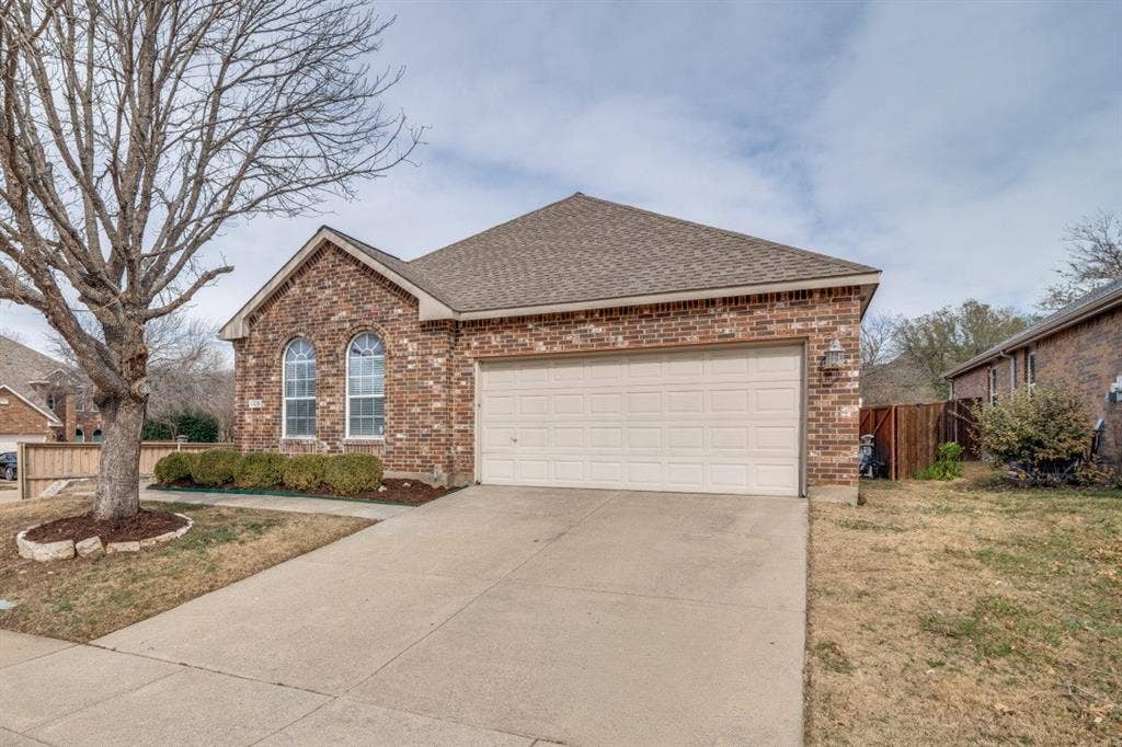 Brick exterior with arched windows, an attached two-car garage, and a concrete driveway