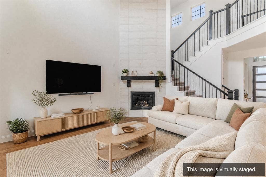 2515 Bedford Road, Northlake, TX 76226 Two-story living area featuring a fireplace with a mantel, open staircase with wrought iron balusters, and transom windows