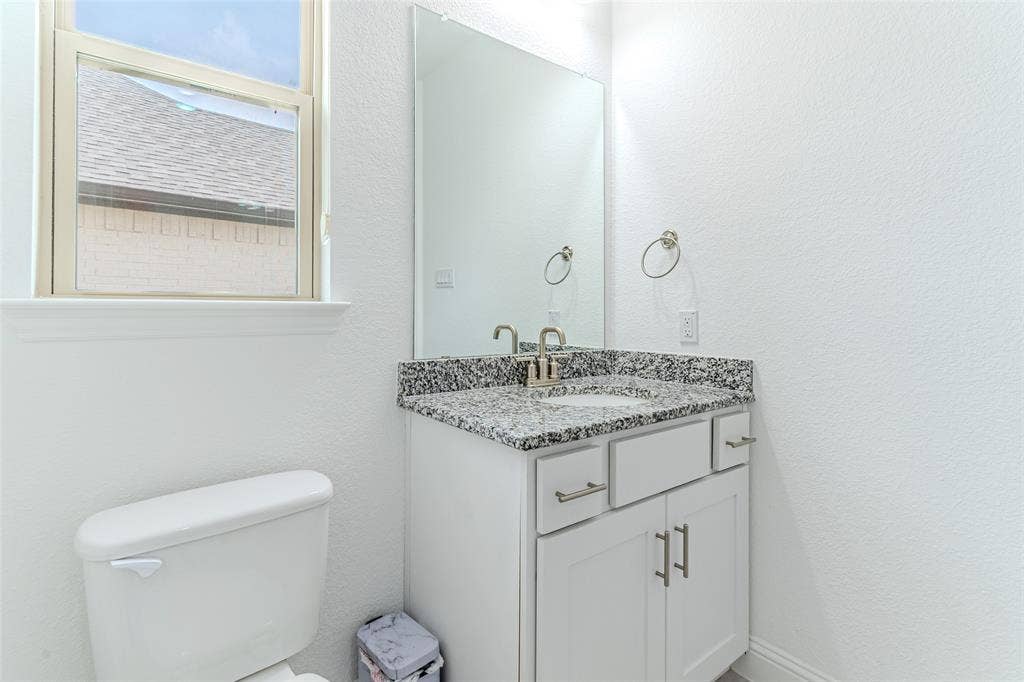 2515 Bedford Road, Northlake, TX 76226 White vanity with a speckled countertop, a mirrored wall, and a single window