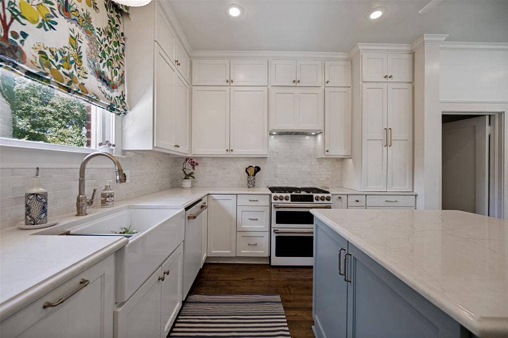 5610 Gaston Avenue, Dallas, TX 75214 White cabinetry with brushed nickel hardware, expansive countertop space, white subway tile backsplash, farmhouse-style sink, and wood-finish flooring