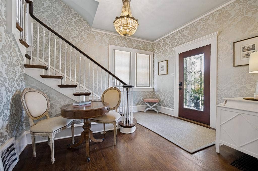 5610 Gaston Avenue, Dallas, TX 75214 Ornate chandelier, wood-finish flooring, staircase with white balusters, decorative wall covering, and a front door with leaded glass
