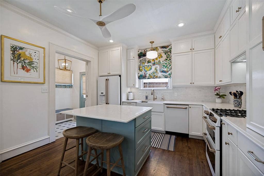 5610 Gaston Avenue, Dallas, TX 75214 White shaker cabinetry, wood-finish flooring, central island with light countertop, built-in stainless steel appliances, and white subway tile backsplash