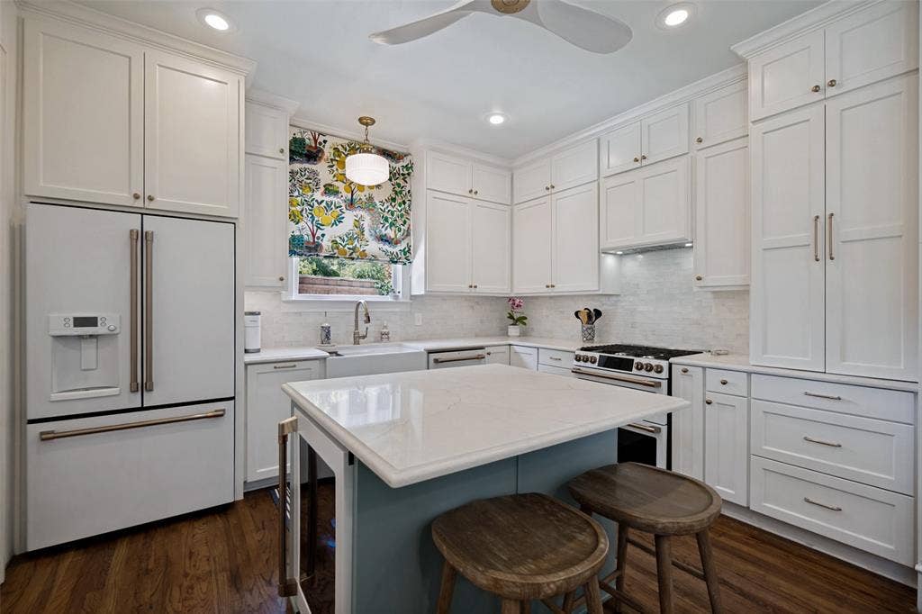 5610 Gaston Avenue, Dallas, TX 75214 Crisp white cabinetry, wood-finish flooring, central island with seating, stainless steel appliances, and recessed lighting