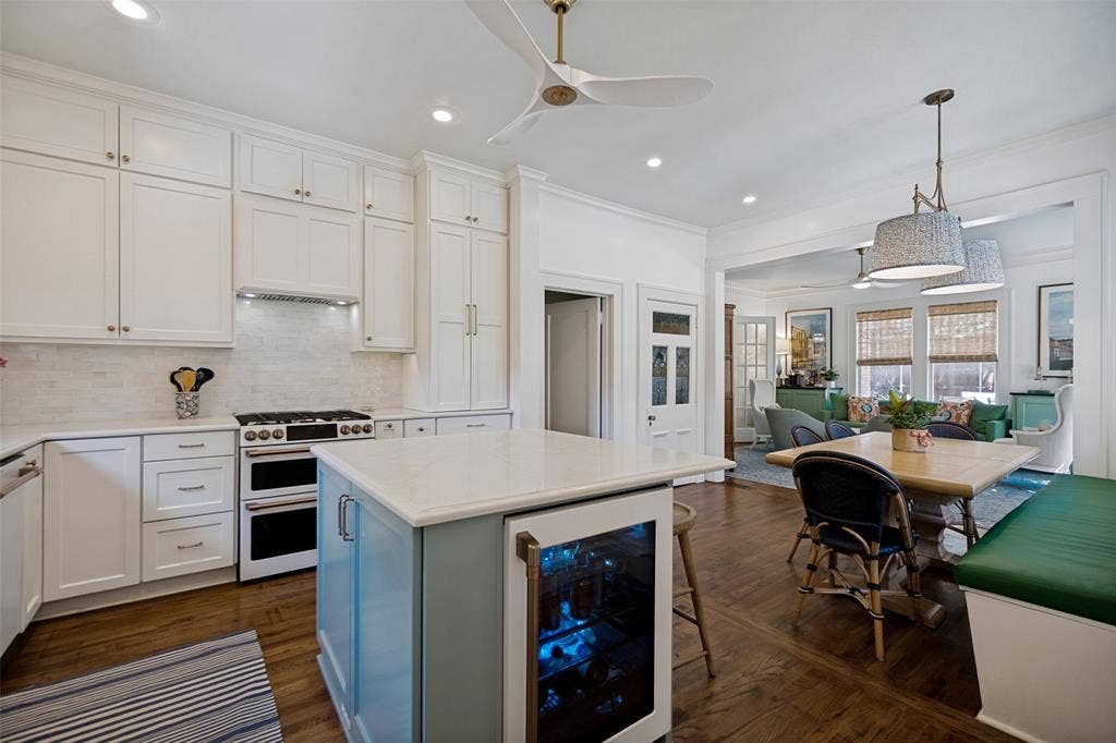 5610 Gaston Avenue, Dallas, TX 75214 Gourmet kitchen featuring a double oven range, white shaker cabinetry, white subway tile backsplash, and a center island with integrated beverage refrigerator