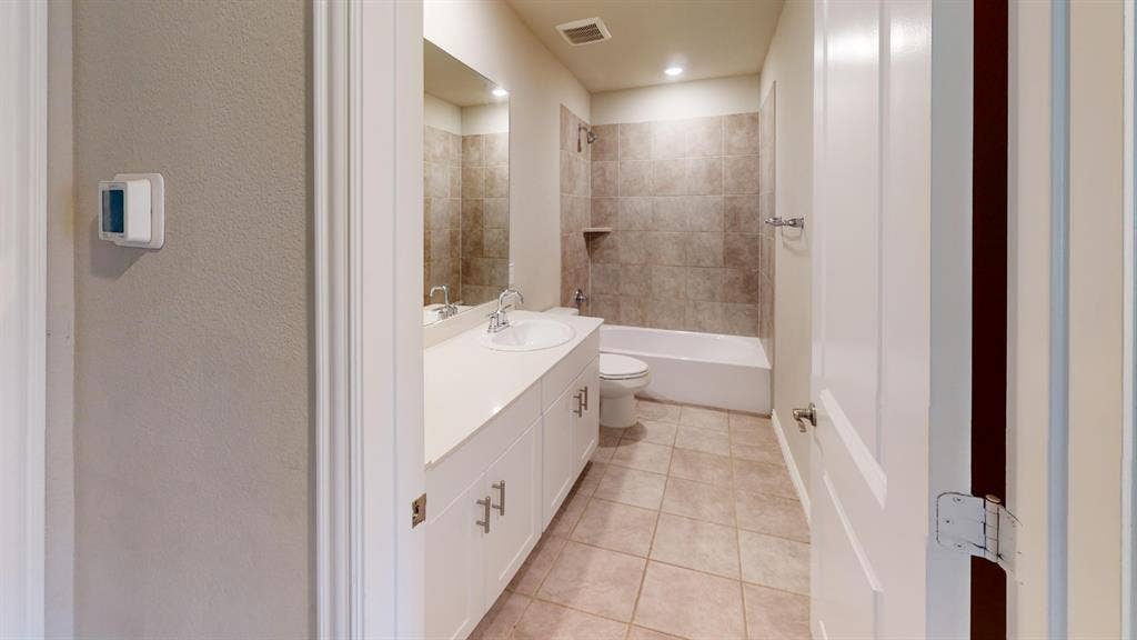 1508 Lannon Lane, Melissa, TX 75454 Bathroom featuring a double vanity with an undermount sink, white cabinetry, a tiled shower/tub combination, and tiled flooring