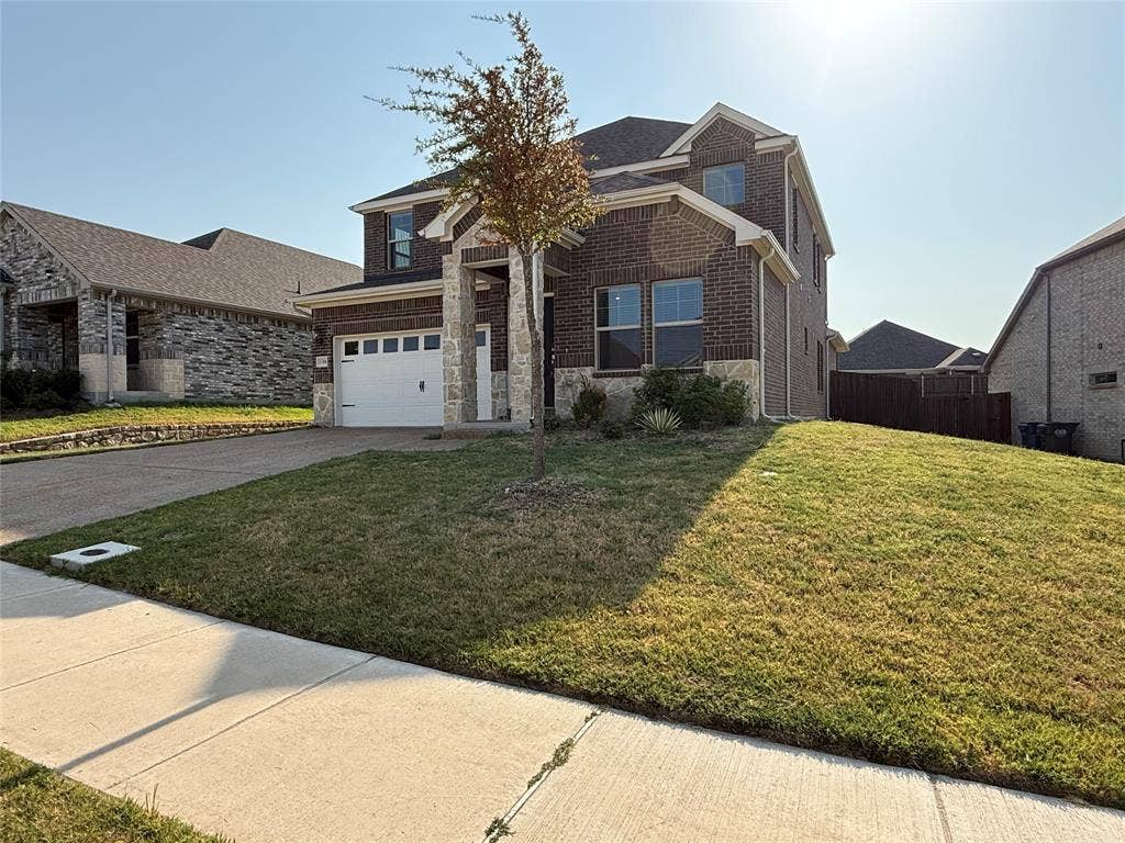 1508 Lannon Lane, Melissa, TX 75454 Brick and stone veneer exterior with a two-car garage, concrete driveway, and established front yard landscaping
