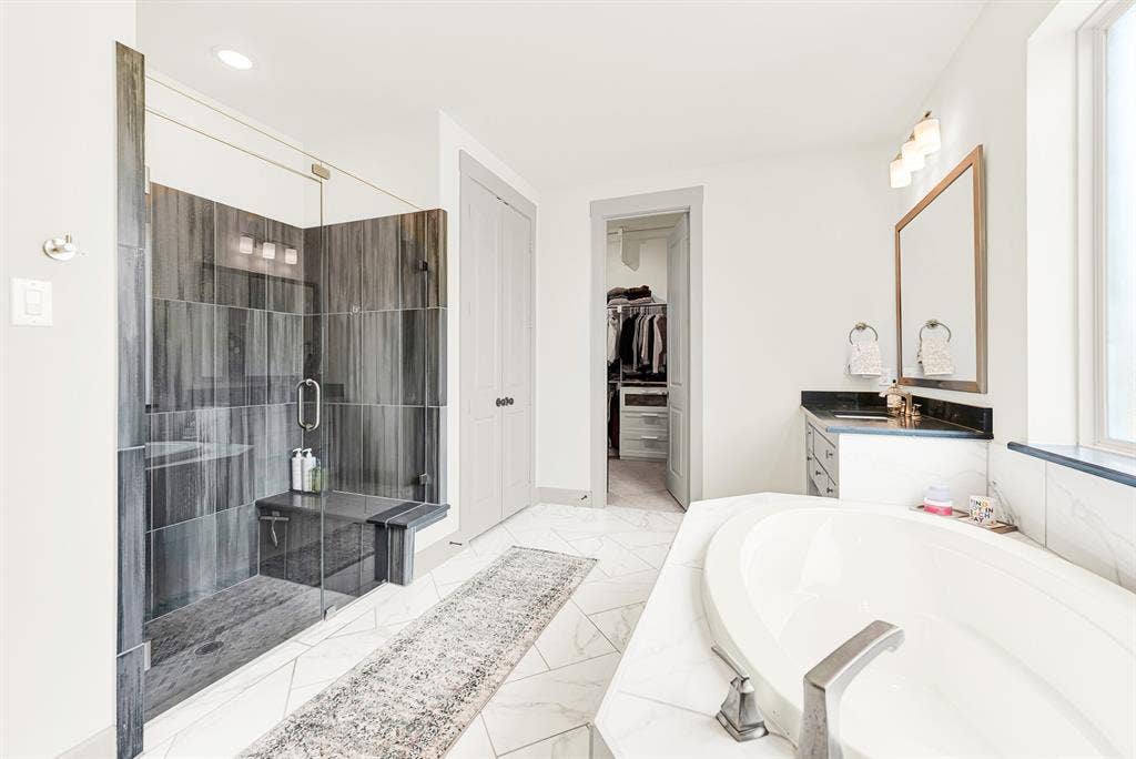 10067 Clover Forest Court, Frisco, TX 75035 Dark vertical tilework creates bold contrast inside a glass walk-in shower set beside pristine marble counters. Imagine starting brisk morning routines with an invigorating, spa-like shower experience.