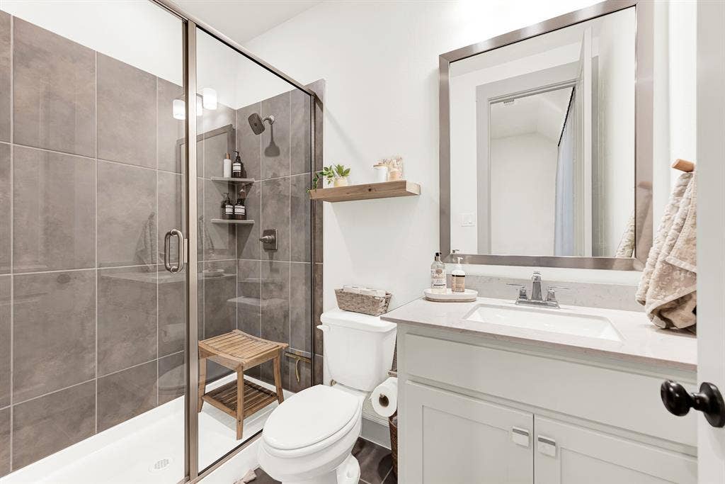 10067 Clover Forest Court, Frisco, TX 75035 Sleek glass enclosures and rich floor-to-ceiling shower tiles create a modern design frame that catches bright, clean lighting. Visitors can wind down with a hot, spa-like rinse after a long day of travel, enjoying complete privacy and comfort.