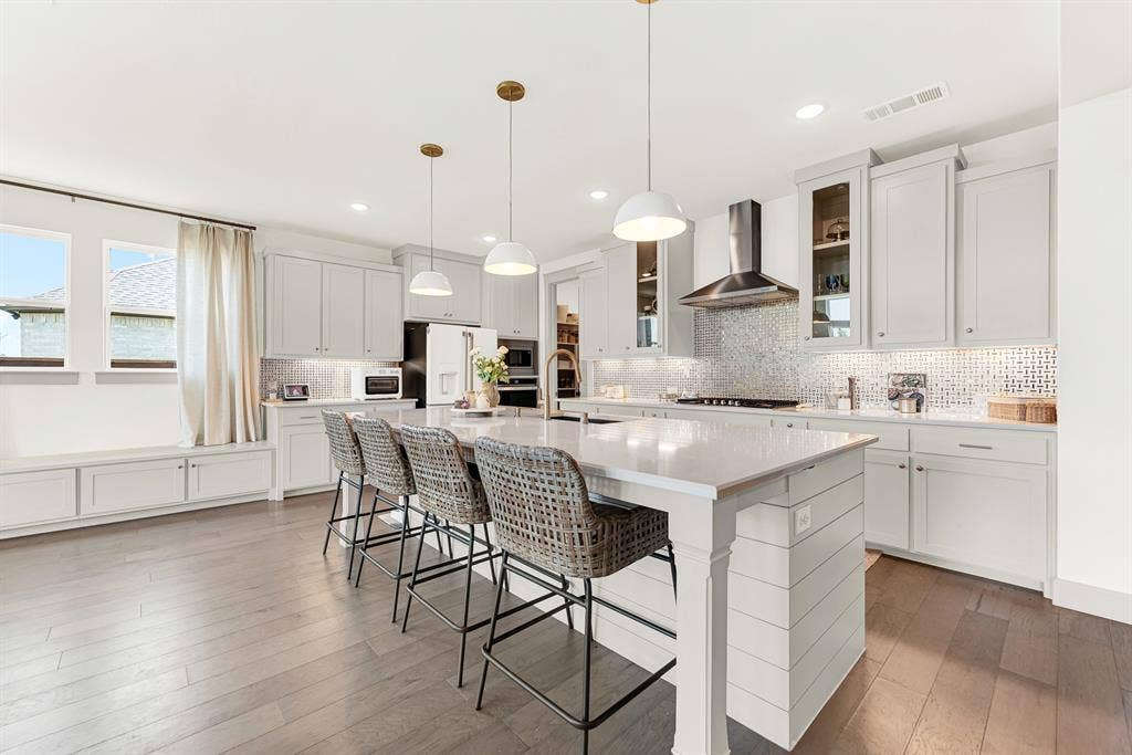 10067 Clover Forest Court, Frisco, TX 75035 Trio pendant lights illuminate an expansive central prep island anchored by a cozy window bench. Picture lively weekend brunches where everyone gathers for warm pancakes.