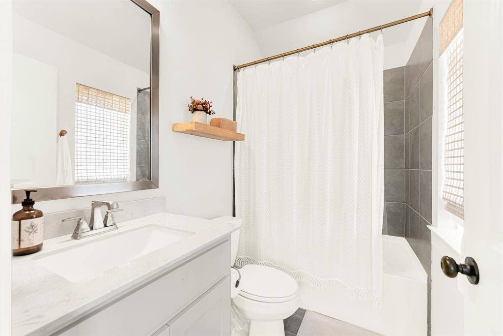 10067 Clover Forest Court, Frisco, TX 75035 A woven window shade softens incoming sunshine beside a crisp, wide vanity mirror setup. Kids can wrap up their evening bedtime routine in a serene, organized bath space.
