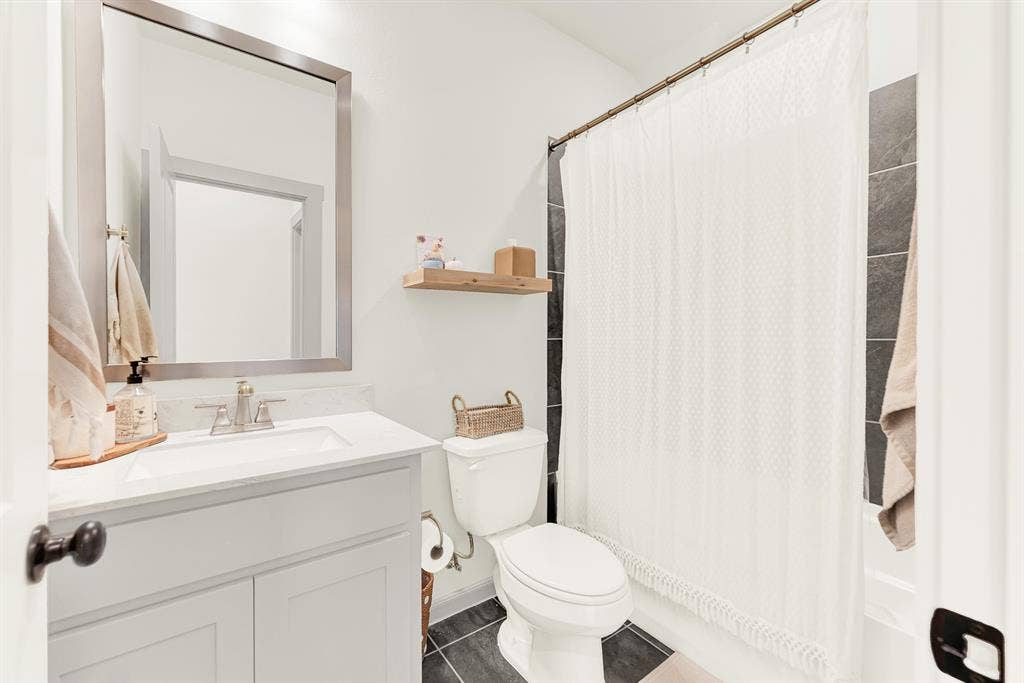 10067 Clover Forest Court, Frisco, TX 75035 Clean white stone counters and dark floor tiles contrast beautifully under soft vanity lighting. Family members can quickly gear up for the day ahead in a bright, orderly setting.