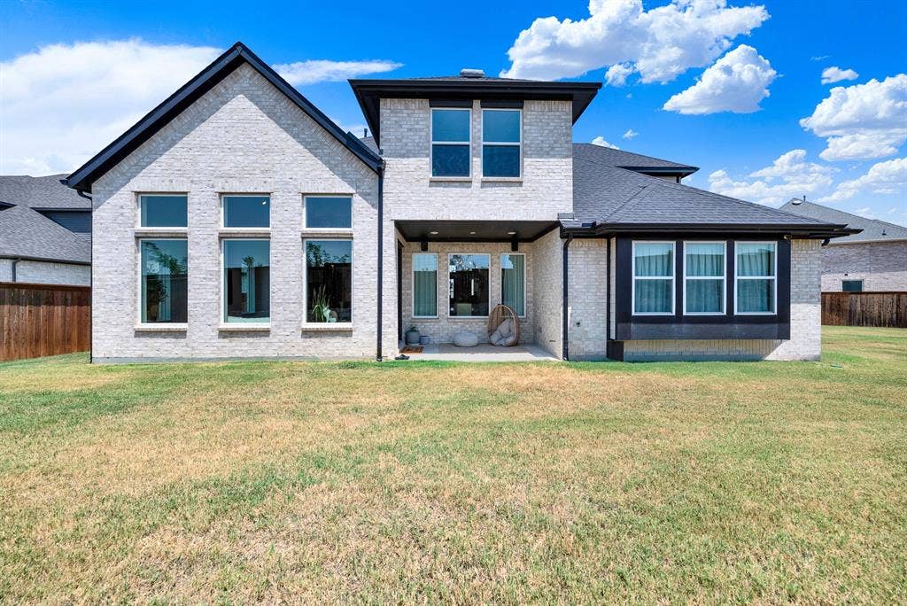 10067 Clover Forest Court, Frisco, TX 75035 A shaded back porch nestles beneath towering window banks that reflect afternoon sunlight across the lawn. You can sip a chilled drink in the breeze while watching the family play outside.