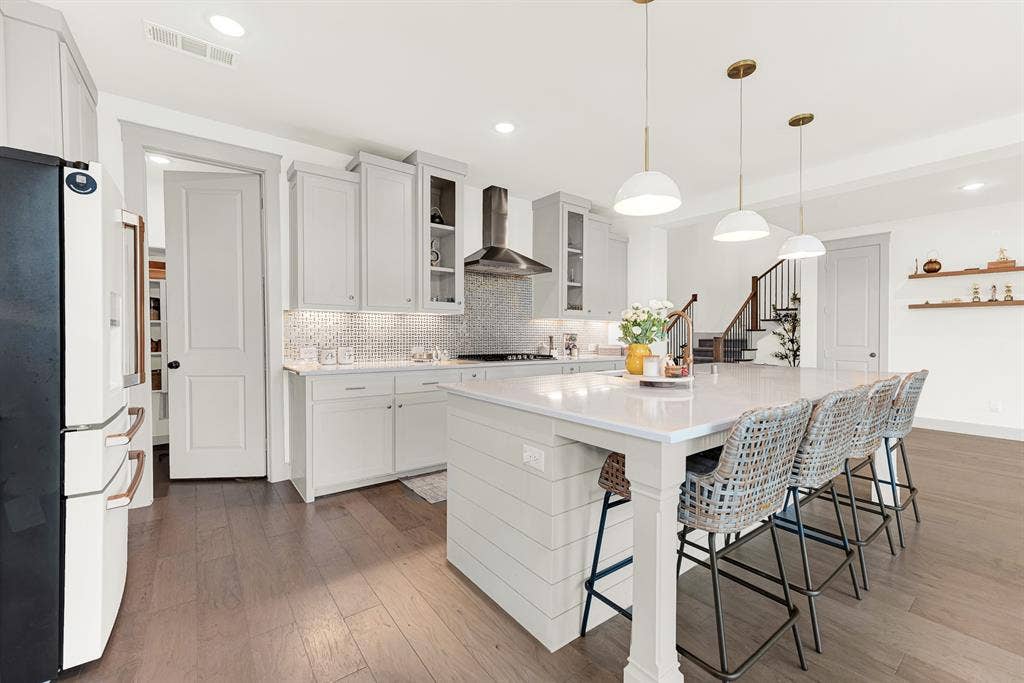 10067 Clover Forest Court, Frisco, TX 75035 Smooth quartz counters frame a sleek pro-style range hood and walk-in pantry doorway. Imagine grabbing late-night snacks together after a movie in the living room.