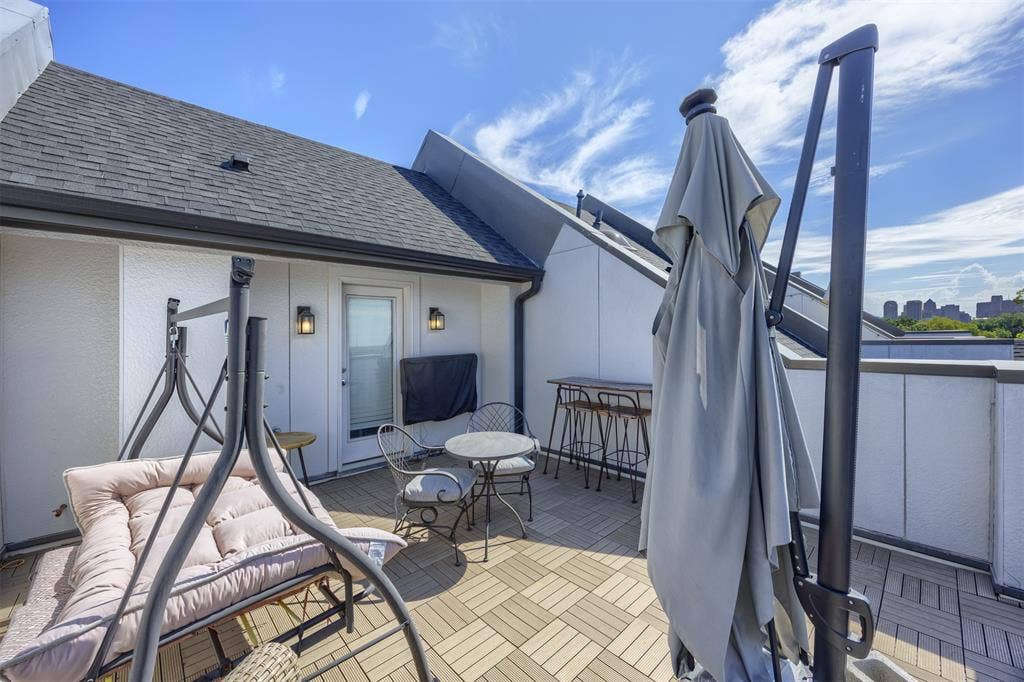 Rooftop terrace with tile-patterned decking, exterior wall sconces, and a white entry door