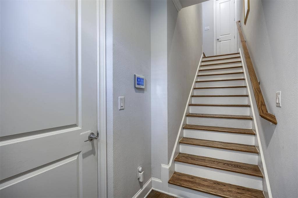 Staircase featuring wood-finish treads and a natural wood handrail