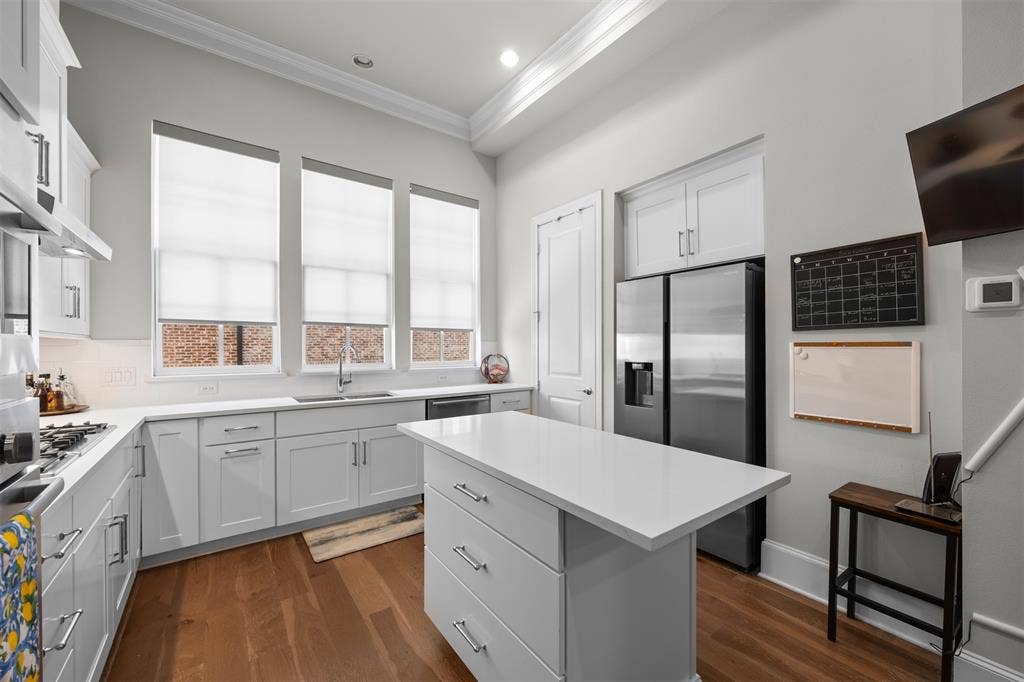 Kitchen featuring white shaker-style cabinetry, an island with countertop seating, wood-finish flooring, recessed lighting, and stainless steel appliances