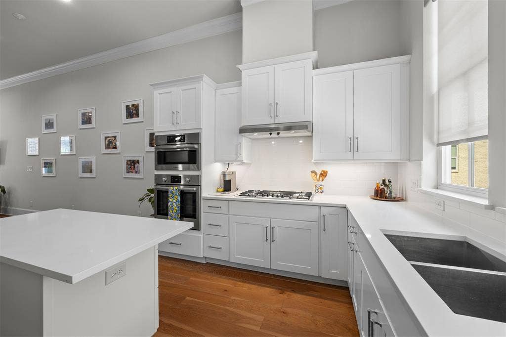 White shaker cabinetry paired with stainless steel appliances, white subway tile backsplash, and light-toned countertops