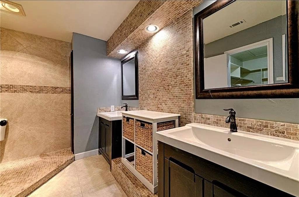 2601 Country Place, Carrollton, TX 75006 Dual vanity sinks with dark wood cabinetry, a mosaic tile backsplash, and recessed lighting
