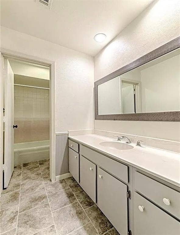 2601 Country Place, Carrollton, TX 75006 Dual basin vanity with white countertop and cabinetry, tile flooring, and a large mirror with a textured frame