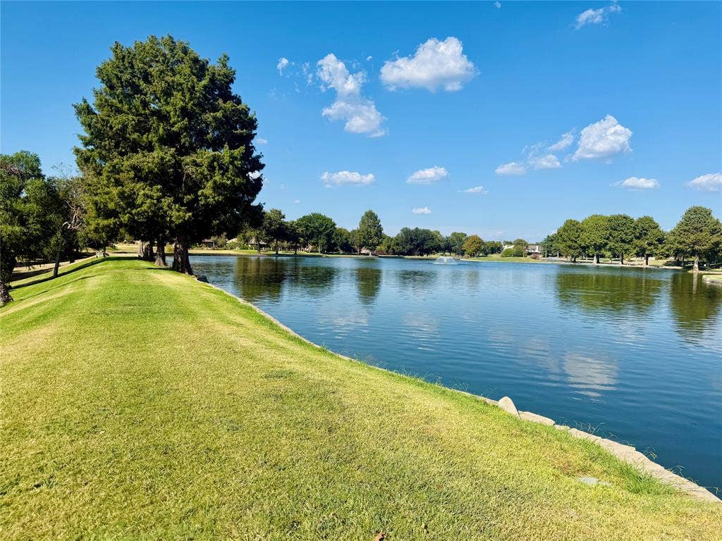2601 Country Place, Carrollton, TX 75006 Waterfront setting with a tranquil lake, mature trees, and a spacious grassy bank