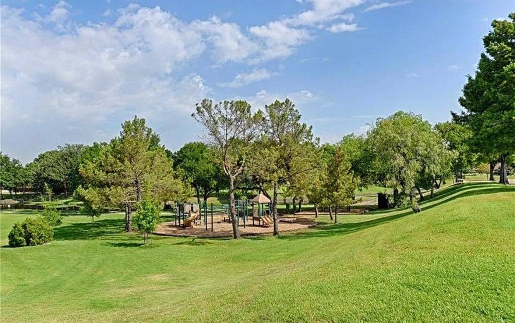 2601 Country Place, Carrollton, TX 75006 Expansive green space featuring a playground, mature trees, and a sloping lawn