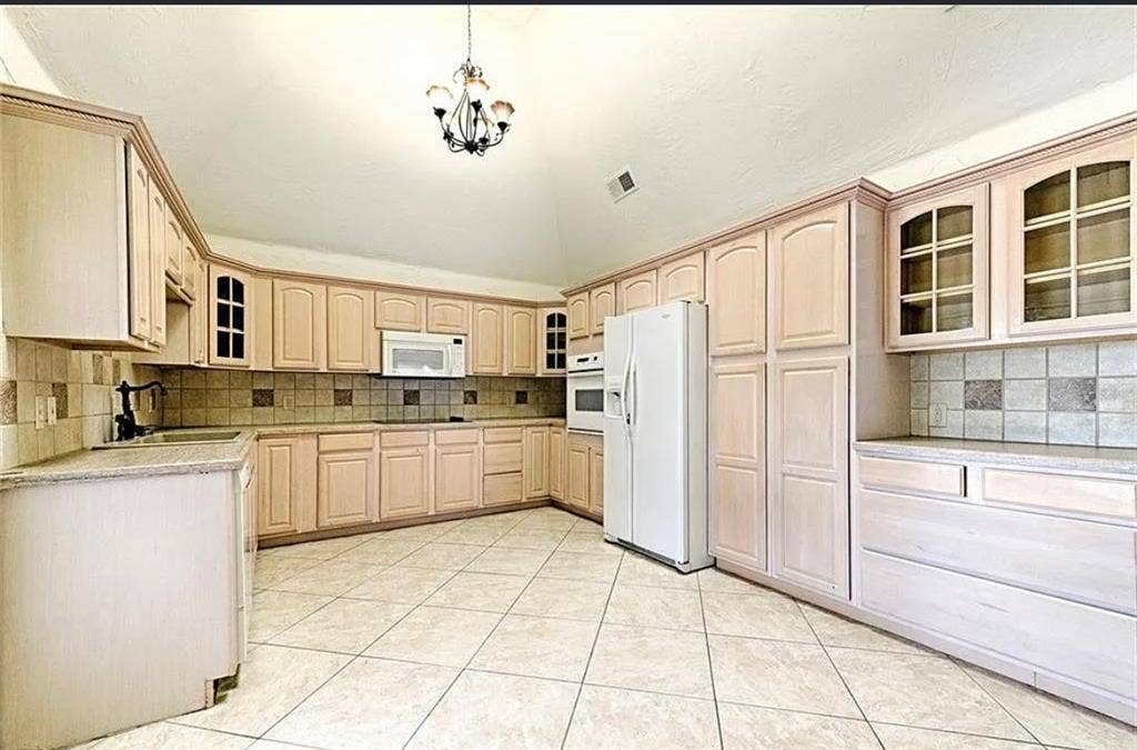 2601 Country Place, Carrollton, TX 75006 Spacious kitchen featuring light wood cabinetry with glass-front upper cabinets, tile backsplash, ceramic tile flooring, and stainless steel appliances including a side-by-side refrigerator and white range