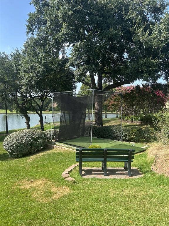 2601 Country Place, Carrollton, TX 75006 Lush green lawn with a golf net, artificial turf putting area, and a dark green slatted bench