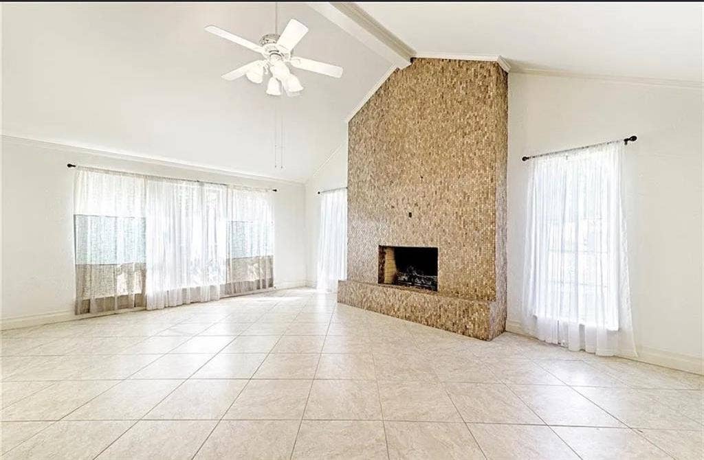 2601 Country Place, Carrollton, TX 75006 Vaulted ceiling featuring a ceiling fan, a large stone-clad fireplace, and tile flooring