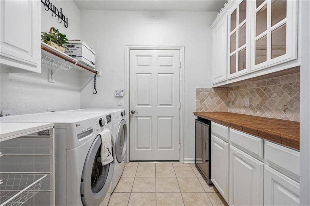 929 Oakland Hills Drive, Fairview, TX 75069 Lots of additional storage with glass front cabinets, wine refrigerator, lower roll out cabinet, plus shelving and a cabinet above the washer and dryer area - - door to the garage