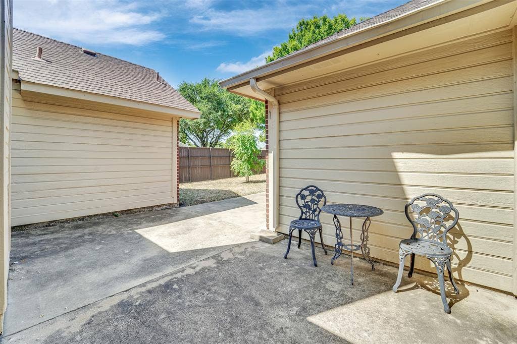 4001 Arrowcrest Lane, Garland, TX 75044 Covered carport with concrete flooring and open-air seating area, framed by horizontal siding and mature landscaping