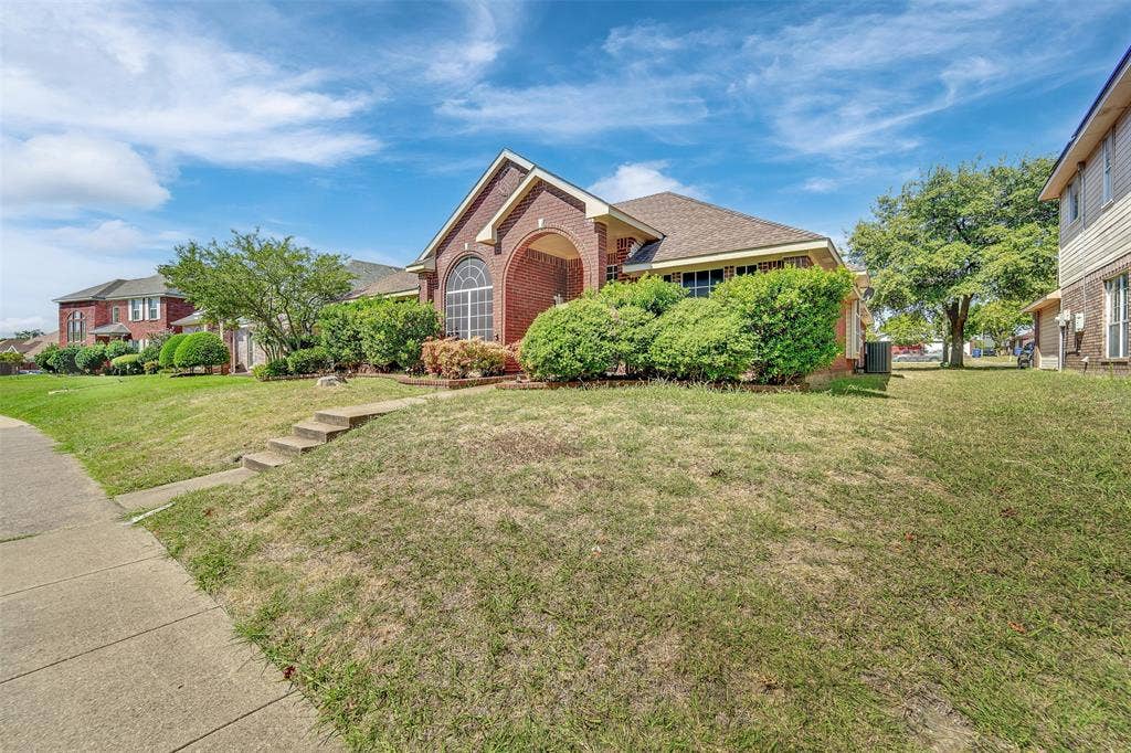 4001 Arrowcrest Lane, Garland, TX 75044 Brick exterior with an arched entry, prominent arched window, and mature front landscaping