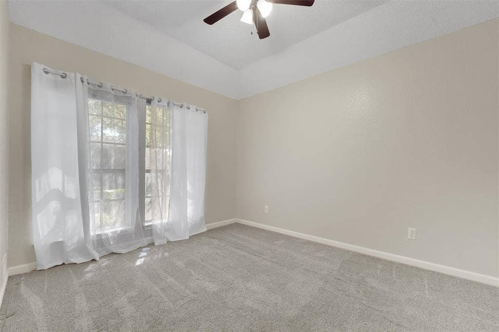 4001 Arrowcrest Lane, Garland, TX 75044 Vaulted ceiling with a ceiling fan, dual windows, neutral wall paint, and grey carpet flooring