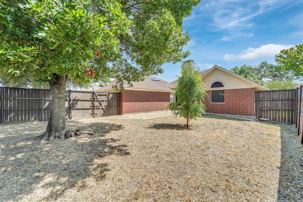 4001 Arrowcrest Lane, Garland, TX 75044 Fenced backyard with mature trees, brick exterior, and an arched window detail