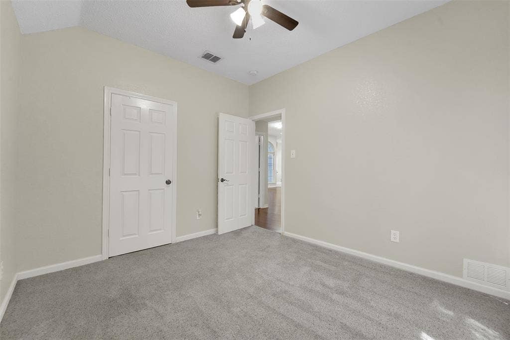 4001 Arrowcrest Lane, Garland, TX 75044 Vaulted ceiling featuring a ceiling fan with integrated lighting, neutral-toned walls, and grey carpeting