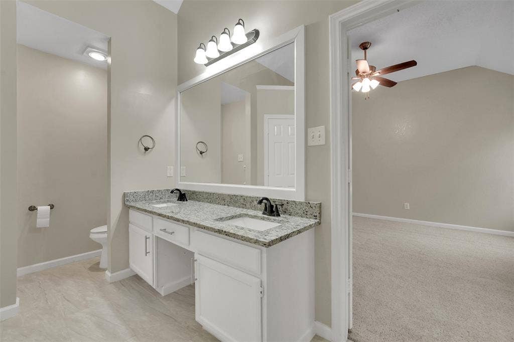4001 Arrowcrest Lane, Garland, TX 75044 Primary bathroom featuring a dual-sink vanity with granite-style countertop, white cabinetry, and polished chrome fixtures