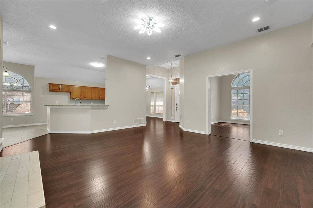 4001 Arrowcrest Lane, Garland, TX 75044 Spacious interior featuring wood-finish flooring, recessed lighting, arched windows, and a kitchen pass-through with a breakfast bar