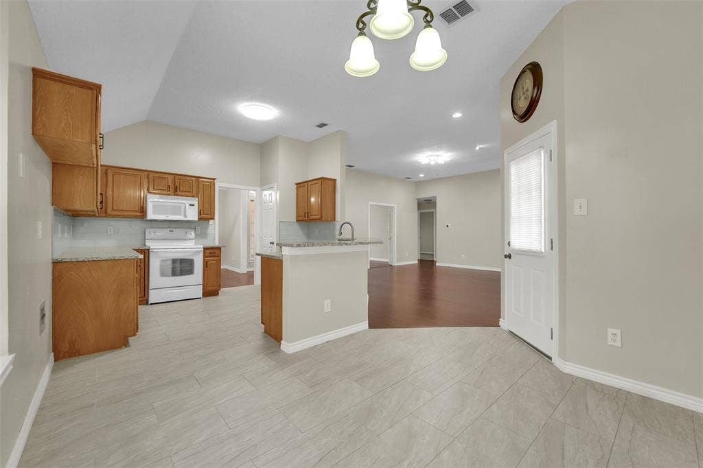 4001 Arrowcrest Lane, Garland, TX 75044 Kitchen featuring wood cabinetry, white appliances, and light-colored tile flooring