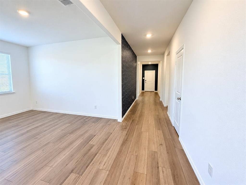 8432 Butterfly Lane, McKinney, TX 75071 Spacious interior featuring wood-finish flooring, recessed lighting, a window with horizontal blinds, and a textured accent wall