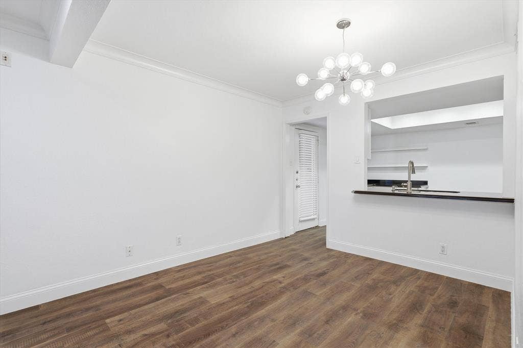 10207 Regal Oaks Drive, #109, Dallas, TX 75230 Dining area positioned conveniently between the living room and kitchen, with an open pass-through connecting the spaces and a rear kitchen entry and exit to the condo.