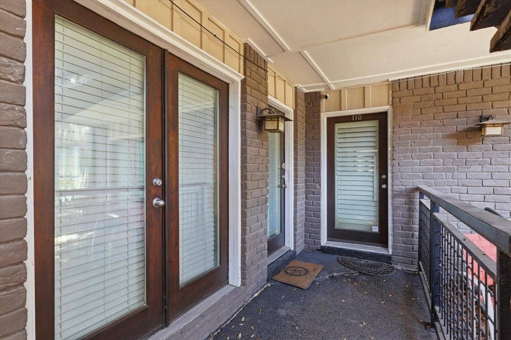 10207 Regal Oaks Drive, #109, Dallas, TX 75230 Covered exterior walkway leading to the condo, providing a view of the building’s courtyard-style setting.