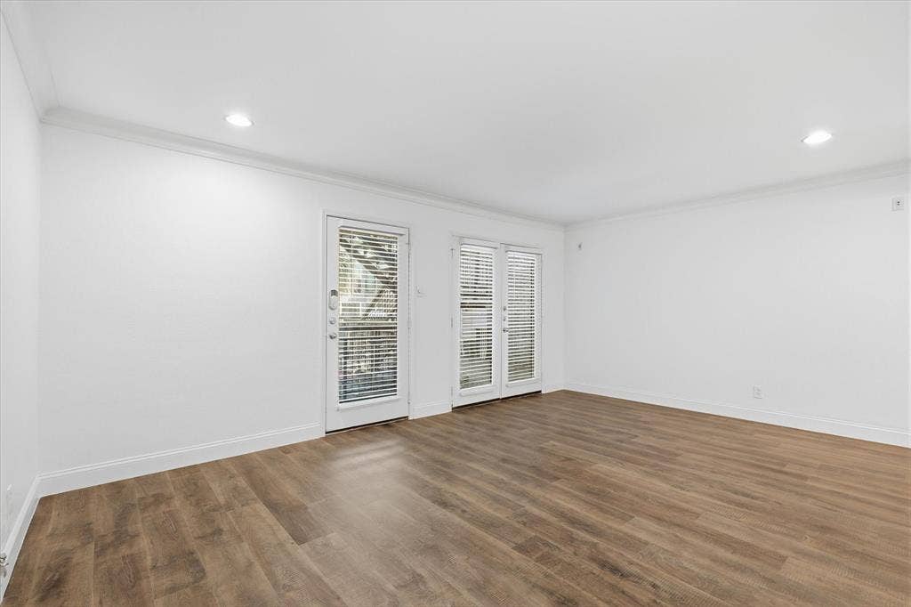10207 Regal Oaks Drive, #109, Dallas, TX 75230 Living area with French doors providing natural light and access to the outdoor patio.